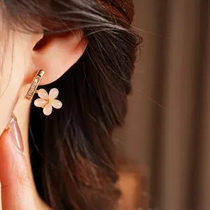 Elegant gold earrings featuring pink resin flowers and sparkling zircon stones on model