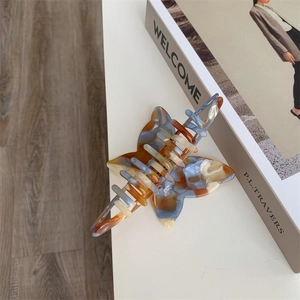 Close-up of elegant marble pattern bow hair claw with blue and amber resin textures