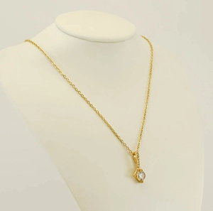 Close-up of gold-plated stainless steel necklace with diamond pendant on a jewelry bust