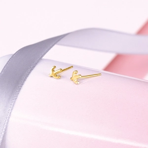 Macro shot of polished gold cactus stud earrings on light pink pedestal stand