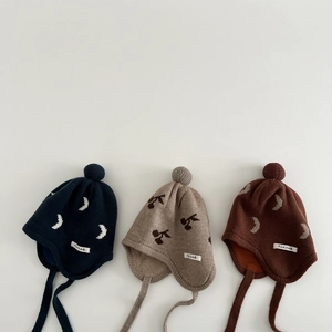 Three warm baby knit hats with pom poms and moon/cherry patterns in navy, beige, and brown