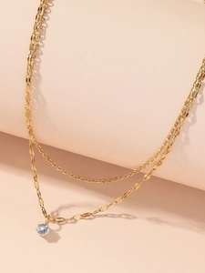 Detailed macro view of a double-layer gold titanium necklace with clear stone pendant