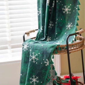 Dark green Christmas blanket with white snowflake patterns and tassels for home decor