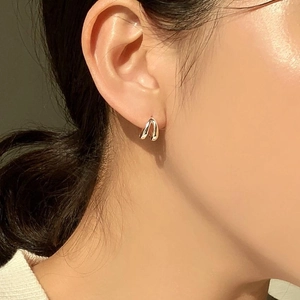 Close-up of golden dual-layer twisted hoop earrings showing a polished finish on earlobe