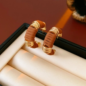 Dettaglio degli orecchini a forma di C in pelle marrone con accenti dorati