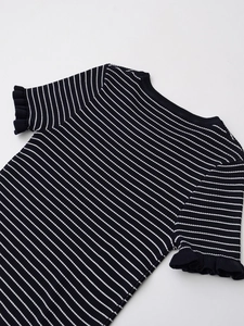 Détail d'un haut en maille rayé avec poignets à volants et texture tricotée délicate