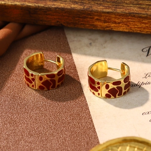 Detail of gold enamel hoop earrings with red giraffe pattern on vintage leather