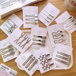 Detailed view of silver Y2K star and heart hair clips on handmade card packaging