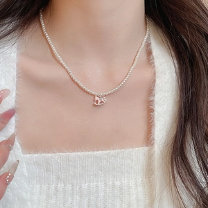 Detailed view of pearl necklace with silver rocking horse pendant on a knit sweater