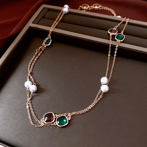 Detail of vintage gold layered necklace with glass pearls and colorful square gemstones