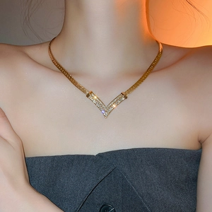 Detailed close-up of a gold-plated V-shaped necklace with sparkling rhinestones on neck
