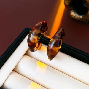 Macro shot of amber leopard print resin C-shaped hoop earrings in jewelry box