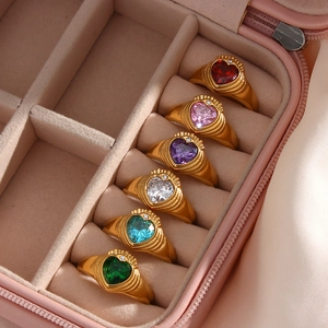 Close-up of six gold rings with multicolored heart gemstones in a velvet jewelry box