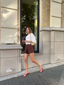 Oversize white T-shirt with Girl Therapy embroidery paired with brown shorts and flip-flops