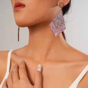 Close-up of ethnic style wooden diamond-shaped earrings with red pattern print on model