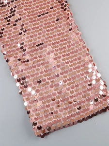 Detail of rose gold fish scale sequins on pink mesh fabric for elegant evening dresses