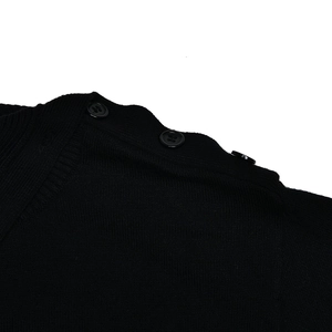 Detailed macro view of black knit fabric texture and decorative shoulder buttons