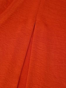 Close-up of orange satin fabric showing detailed pleated texture and fine stitching