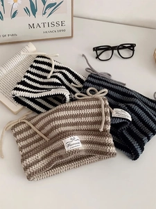 Detailed macro view of striped knit beanies with bow ties and handmade labels in various colors