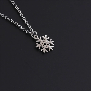 Detailed view of polished stainless steel snowflake pendant necklace on dark background