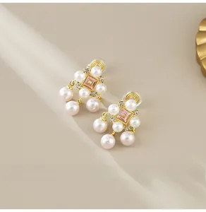 Macro view of gold pearl earrings with pink zircon stone and clip-on design for women