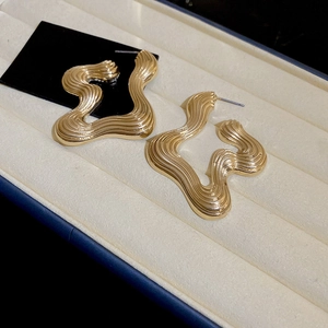 Macro view of gold irregular wavy earrings with detailed ribbed texture on velvet