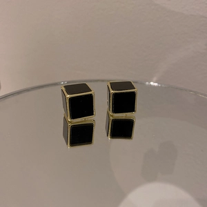 Gros plan détaillé de boucles d'oreilles cubes géométriques noires et dorées sur miroir
