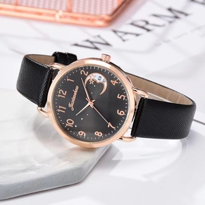 Detailed shot of black dial watch with rose gold case and moon star pattern on marble