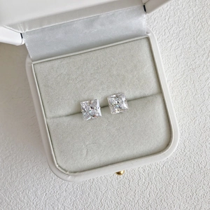 Detail of square white zircon stud earrings set in a premium white jewelry gift box