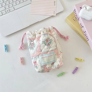 Close-up of pink quilted drawstring pouch with floral pattern and Sorakka Studio label