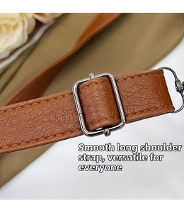 Close-up of adjustable brown leather shoulder strap with silver metal buckle detail