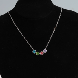 Détail du collier argenté avec une rangée courbe de zircons bleus, verts, rouges et violets