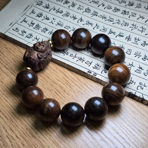 Vue détaillée de perles de bois d'agar avec pendentif Bouddha sur un bureau en bois brun