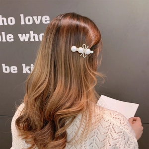 Close-up of hair clip with three white pearls and a sparkling rhinestone bow detail