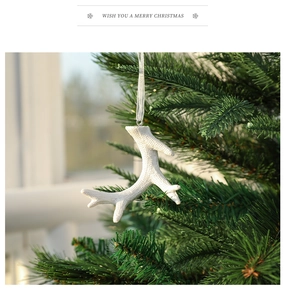 Macro detail of white resin reindeer antler ornament hanging on a green Christmas tree