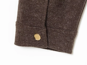 Detailed close-up of dark brown wool jacket cuff with a round gold metallic button