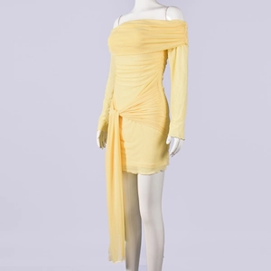 Dettaglio dell'abito corto giallo a spalle scoperte con eleganti drappeggi e pieghe laterali