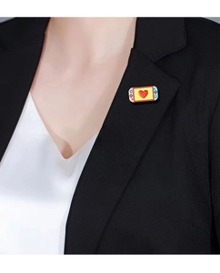 Pink game console enamel pin styled like a handheld device worn on a black blazer lapel