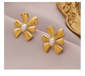 Macro shot of gold floral earrings with white pearls on a purple silk background