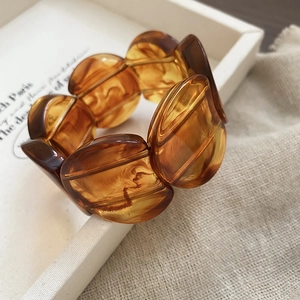 Detail view of amber resin bangle with grooved texture and marble effect on linen