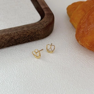 Minimalist gold pretzel shaped heart stud earrings displayed on a rustic wooden tray