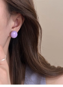 Gros plan d'un mannequin portant une boucle d'oreille ronde violette avec tige en argent