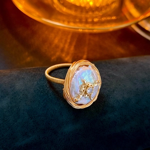Dettaglio macro dell'anello con perla barocca avvolto in filo metallico e zircone