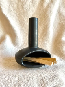 Macro shot of black ceramic Palo Santo burner with wood sticks on a linen cloth