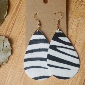 Gros plan de boucles d'oreilles zébrées en cuir avec crochets dorés sur carte kraft