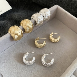 Close-up of woven texture metal C-hoop earrings in gold and silver finishes