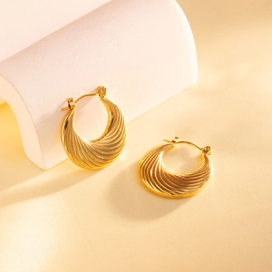 Dettaglio di orecchini a cerchio in oro inossidabile con elegante trama a spirale