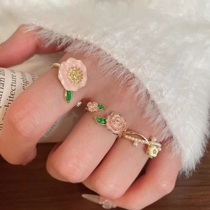 Détail de bagues florales avec fleurs en émail rose et perles sur main de mannequin