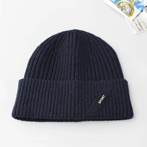Dettaglio del berretto in maglia blu scuro con trama a coste e etichetta Sport nera