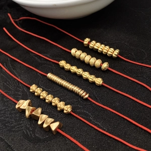 Macro view of assorted golden metal beads in diverse shapes on a red string for DIY jewelry